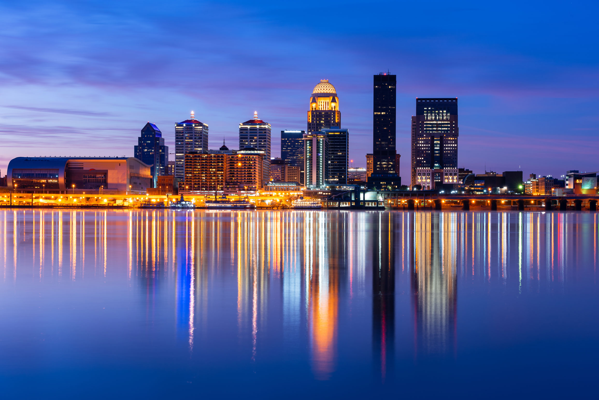 The Louisville, Kentucky skyline at night with lights reflecting off the Ohio River.